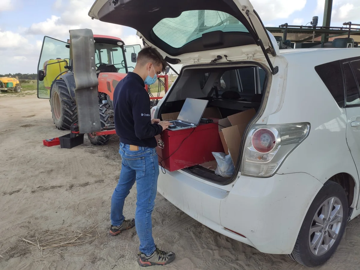 Mario trabajando con un portátil en la configuración de autoguiado junto a maquinaria agrícola